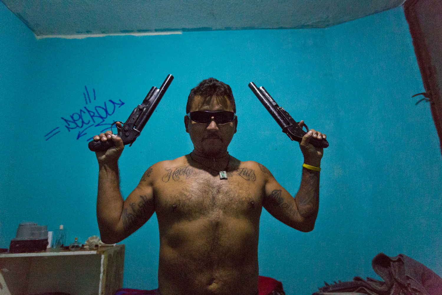 El Mijis stages with guns of the neighborhood on a cartoonish way. He refused the use any arm for a long time ago in order to work in prevention and social area in general.
San Luis Potosi, Mexico - 10/12/2015.

El Mijis pose avec des armes du quartier de manière caricaturale. Ça fait bien longtemps qu’il s’est refusé à leur utilisation pour notamment travailler dans la prévention et le travail social en général.
San Luis Potosi, Mexique - 10/12/2015.