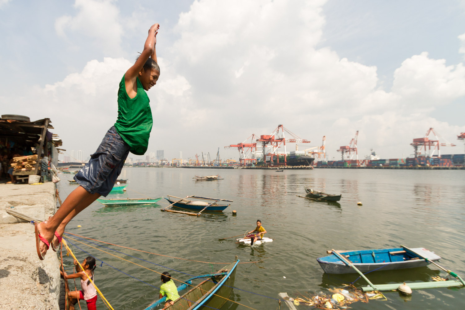 Baseco is an informal neighborhood of Manila located between the international port and the Pasig river. More than 50 000 people are living there in very precarious conditions. 
Children are playing and jumping in the contaminated water of the international port. 
Baseco, Manila, Metro Manila, Philippines - 18/10/2012.