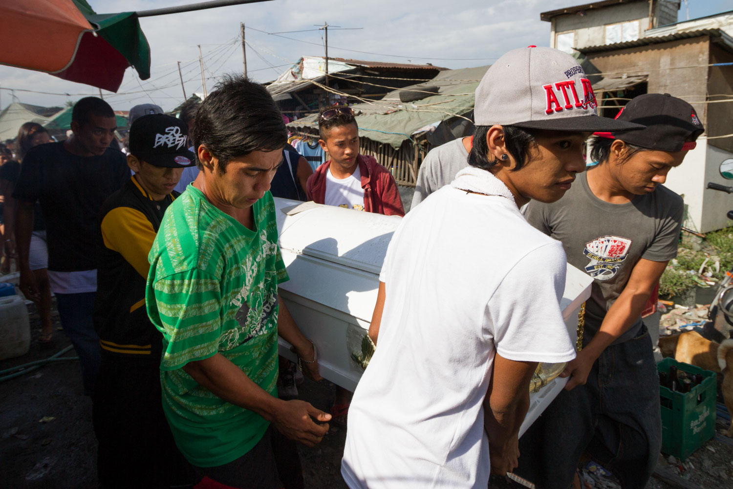 Baseco is an informal neighborhood of Manila located between the international port and the Pasig river. More than 50 000 people are living there in very precarious conditions. 
Friends of Mickael carry its coffin to the hearse. He will get buried in the North Cemetery of Manila. He was shot by a port security guard because he was swiming too near the cranes.  
Manila, Philippines - 21/10/2012.